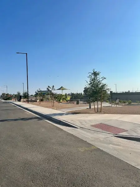 A newly developed street with young trees and a playground in Mayfield by LGI Homes (Buckeye, AZ).