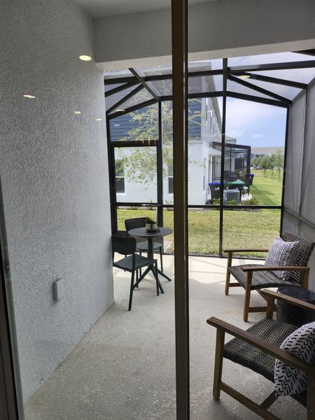 A cozy enclosed patio with a small dining set and wicker chairs, perfect for relaxing and enjoying the outdoor view.