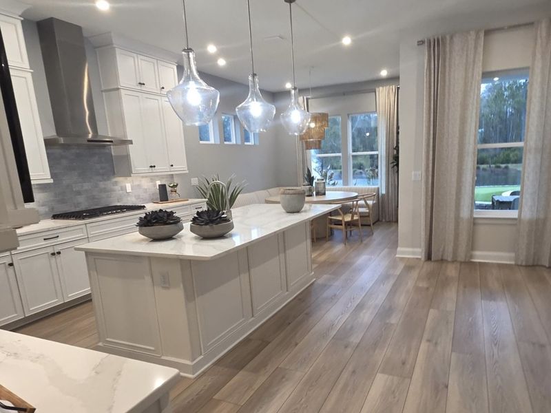 A contemporary kitchen with sleek cabinetry, an island, glass pendant lights, and elegant wood flooring. A contemporary kitchen with sleek cabinetry, an island, glass pendant lights, and elegant wood flooring.