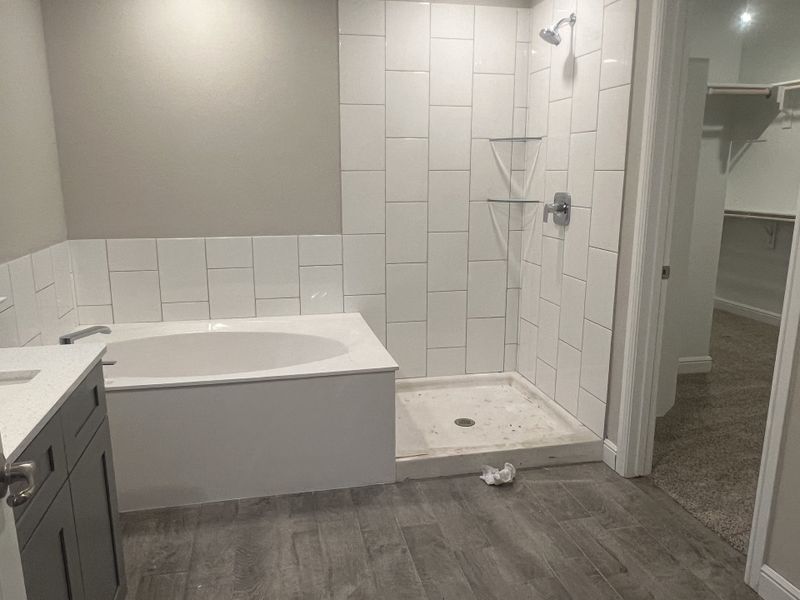 A modern bathroom featuring a sleek soaking tub, spacious walk-in shower with white tiles, and elegant gray cabinetry. A modern bathroom featuring a sleek soaking tub, spacious walk-in shower with white tiles, and elegant gray cabinetry.