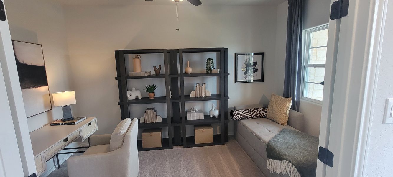 A cozy study with elegant shelving, modern decor, a plush chair, and a stylish daybed.