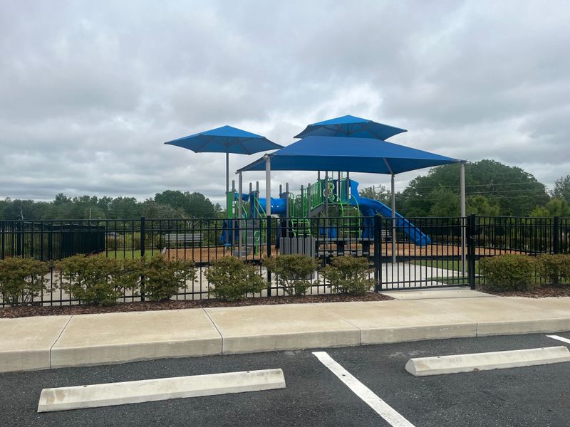 A modern playground with blue canopies and slides in Geneva Landings by Highland Homes of Florida (Davenport, FL).