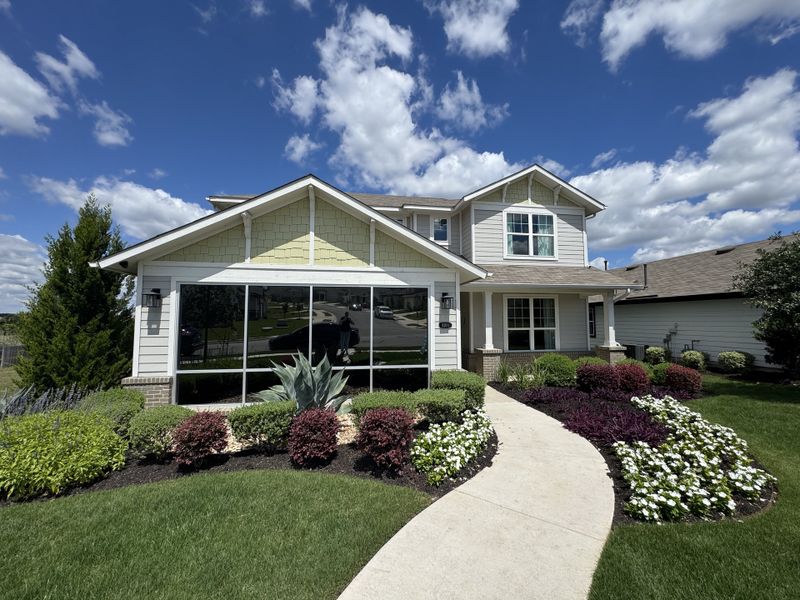 A charming two-story home with a manicured lawn in Cloverleaf by Brohn Homes (Austin, TX).