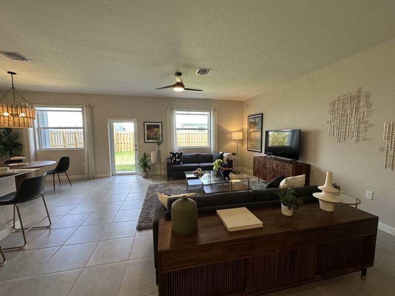 An open-concept living area with modern furnishings, large windows, and a sleek ceiling fan, creating a cozy atmosphere.