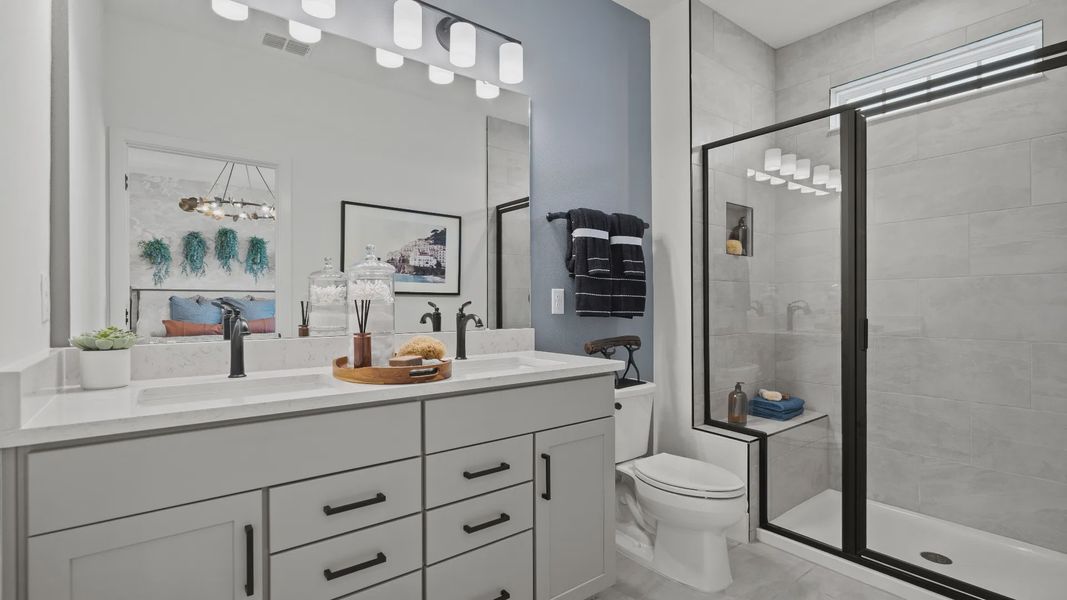The primary suite bathroom at Parkview at Hamlin by DRB Homes offers a spa-like retreat with dual sinks and a walk-in shower