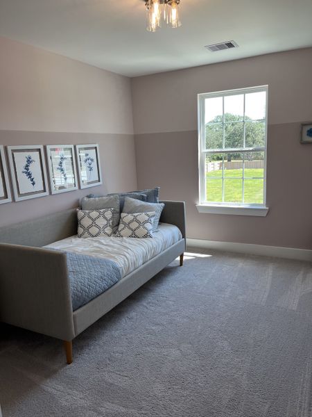 A cozy bedroom with soft pastel walls, a modern daybed, and natural light streaming through a large window.