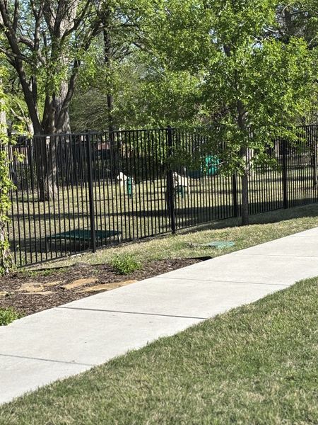 A serene park view with lush greenery and a black iron fence defines Lake Shore Village by Grand Homes (Rowlett, TX). A serene park view with lush greenery and a black iron fence defines Lake Shore Village by Grand Homes (Rowlett, TX).