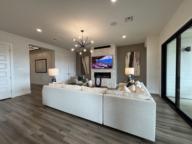 A modern living room with sleek wood floors, chic light fixtures, and a cozy sofa facing a stylish fireplace.