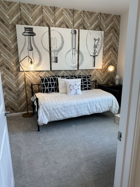 A cozy bedroom with a modern industrial design, featuring herringbone wallpaper, graphic art, and a sleek metal daybed. A cozy bedroom with a modern industrial design, featuring herringbone wallpaper, graphic art, and a sleek metal daybed.