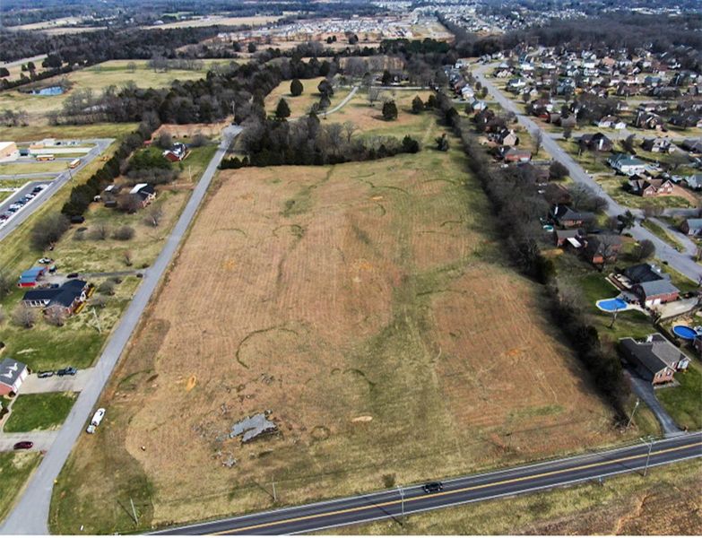 A road with a field and houses.