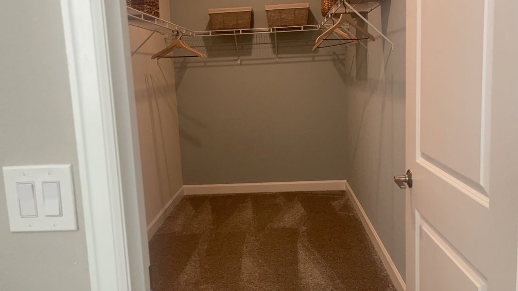 A spacious walk-in closet with sleek wire shelving, elegant hangers, and cozy carpet flooring.