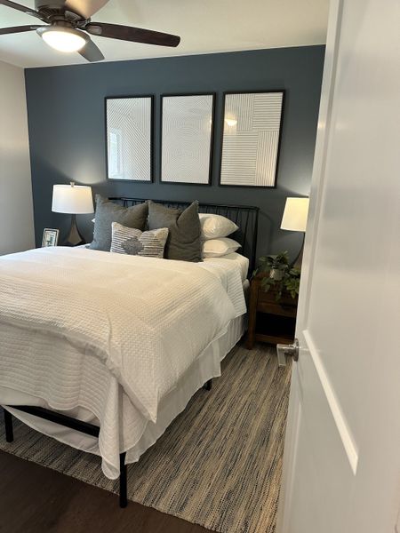 A cozy bedroom featuring a dark accent wall, modern art, plush bedding, and warm lighting for a relaxing atmosphere. A cozy bedroom featuring a dark accent wall, modern art, plush bedding, and warm lighting for a relaxing atmosphere.