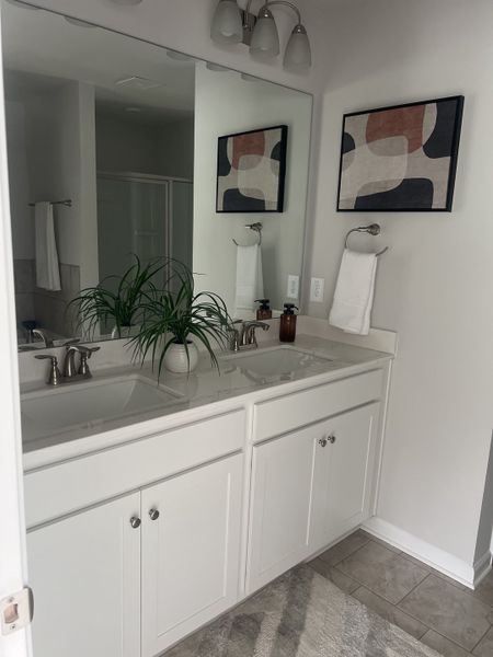 A modern bathroom with a double vanity, elegant fixtures, abstract artwork, and lush greenery for a fresh touch. A modern bathroom with a double vanity, elegant fixtures, abstract artwork, and lush greenery for a fresh touch.