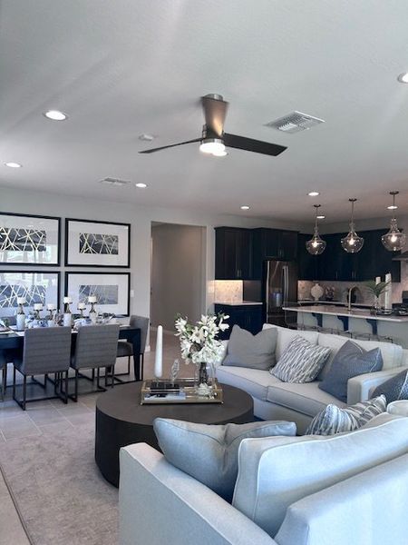 A modern living area with elegant sofas, a chic dining table, and a sleek kitchen featuring dark cabinetry and stylish lighting. A modern living area with elegant sofas, a chic dining table, and a sleek kitchen featuring dark cabinetry and stylish lighting.
