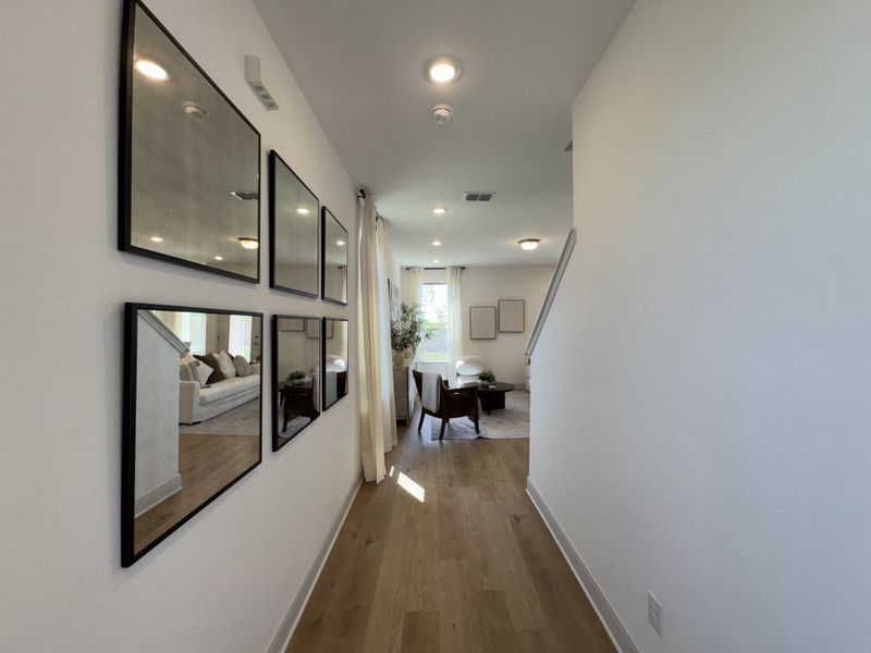 A bright hallway with elegant mirrors, wooden flooring, and a glimpse of the living area in the background. A bright hallway with elegant mirrors, wooden flooring, and a glimpse of the living area in the background.