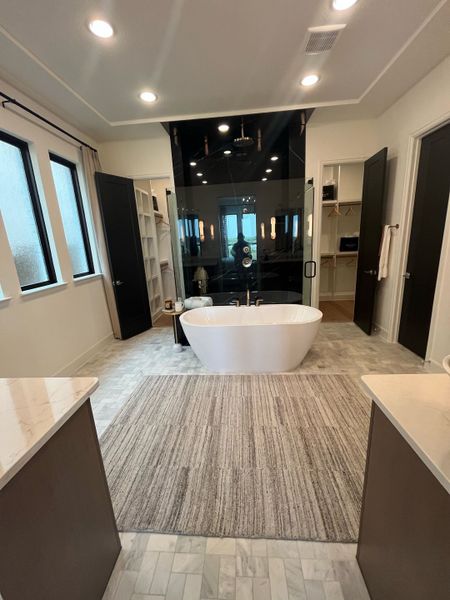 A luxurious bathroom with a sleek freestanding tub, spacious marble flooring, and ample natural light.