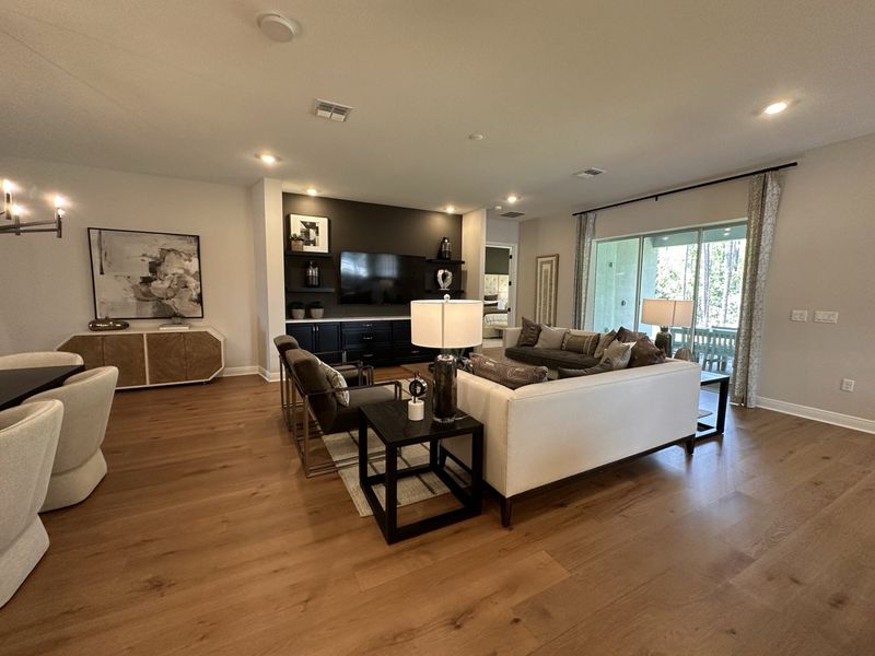 A stylish living area with sleek wood flooring, cozy seating, modern decor, and large windows for ample natural light.