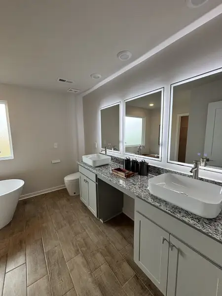 Contemporary bathroom featuring dual vanities, granite counters, wood-look tile, and a freestanding tub. Contemporary bathroom featuring dual vanities, granite counters, wood-look tile, and a freestanding tub.