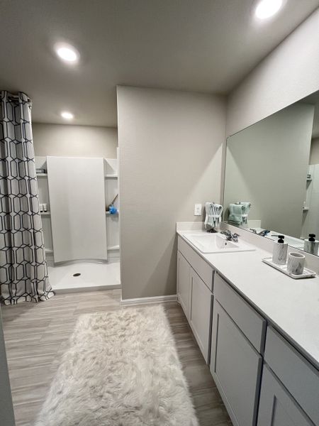 Elegant bathroom with a spacious shower, large mirror, cozy rug, and modern lighting. Elegant bathroom with a spacious shower, large mirror, cozy rug, and modern lighting.