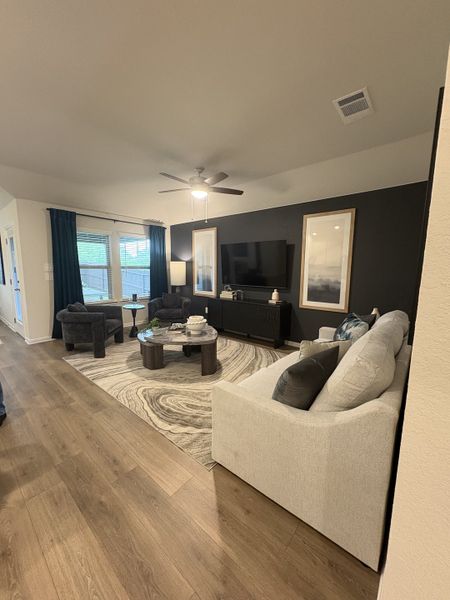 A cozy living room with wood floors, a neutral sofa, and a rug. Features include a navy accent wall and modern decor. A cozy living room with wood floors, a neutral sofa, and a rug. Features include a navy accent wall and modern decor.