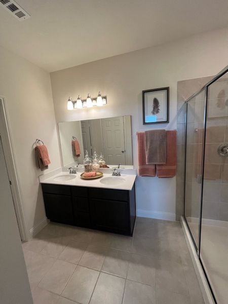 A contemporary bathroom with a double sink vanity, glass shower, and elegant lighting creates a modern, inviting space.