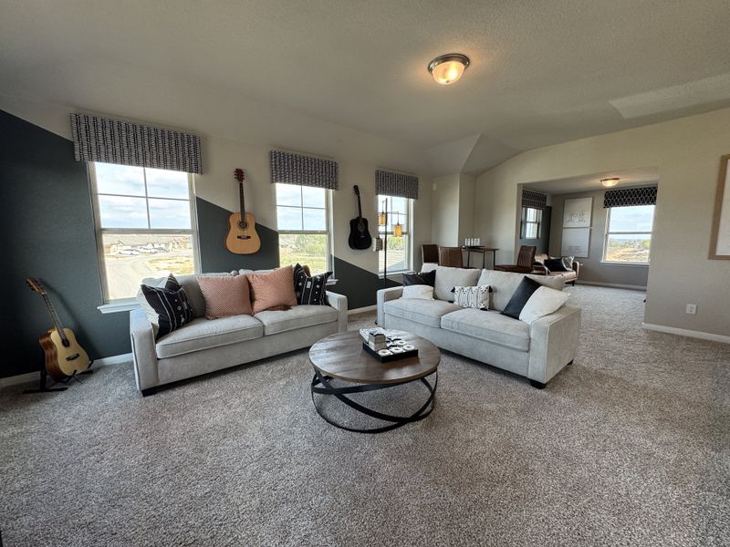 A cozy living room featuring plush sofas, guitars, and modern decor with natural light streaming through large windows.