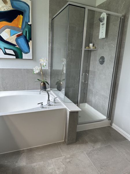 Modern bathroom with a spacious bathtub, sleek glass shower, abstract art, and elegant gray tiles. Modern bathroom with a spacious bathtub, sleek glass shower, abstract art, and elegant gray tiles.