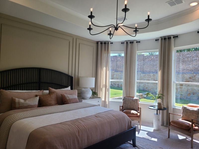 A cozy bedroom featuring elegant panel walls, a plush bed, and large, sunlit windows with chic seating and stylish lighting. A cozy bedroom featuring elegant panel walls, a plush bed, and large, sunlit windows with chic seating and stylish lighting.