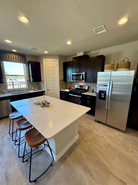 Modern kitchen with sleek dark cabinets, stainless steel appliances, and a spacious island with seating.