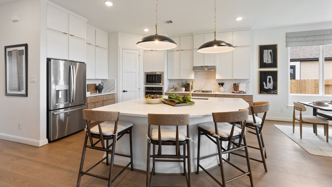 Spacious, bright kitchen featuring white cabinetry and a large island in the Rosewood Model in Grand Magnolia.