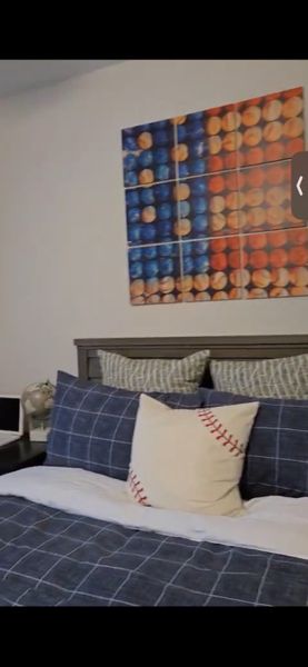 A cozy bedroom with sports-themed art, plaid bedding, and a baseball pillow, creating a playful atmosphere.