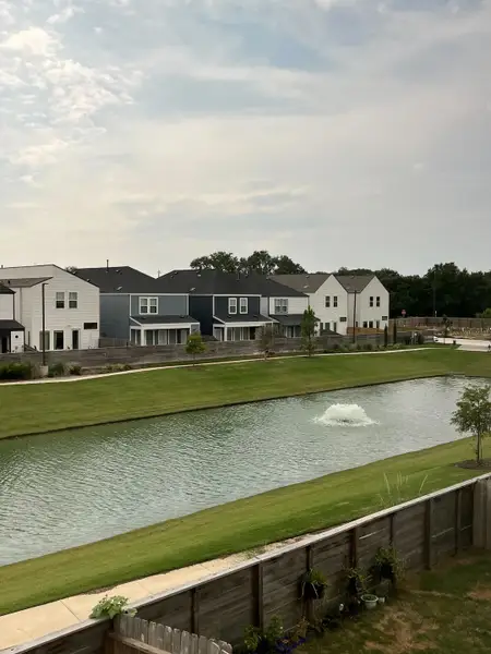 A picturesque community pond with elegant homes lining the shore in Cay Landing by First America Homes (Houston, TX).