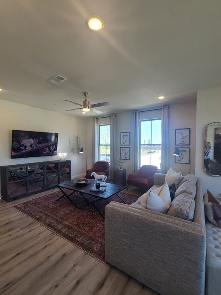 A cozy living room with modern decor, featuring a large TV, stylish furniture, and a warm rug on wood flooring. A cozy living room with modern decor, featuring a large TV, stylish furniture, and a warm rug on wood flooring.