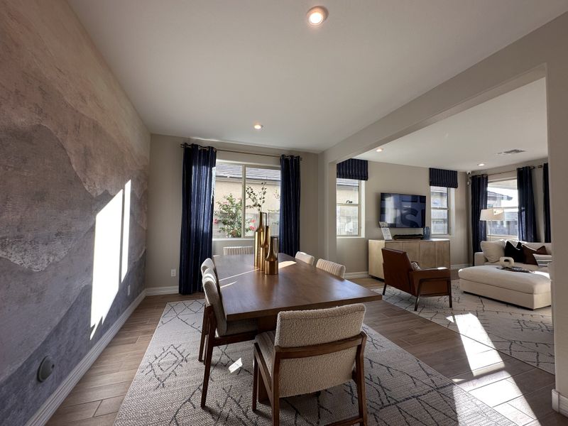 A contemporary dining area with a large table, textured accent wall, and cozy living space in view, enhancing natural light.