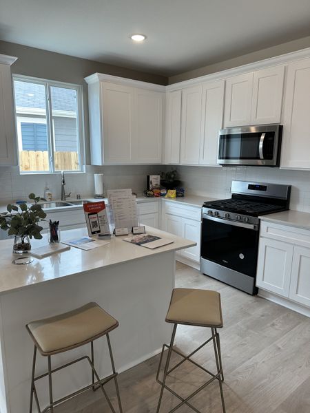 A modern kitchen featuring sleek white cabinets, quartz countertops, and stainless steel appliances.