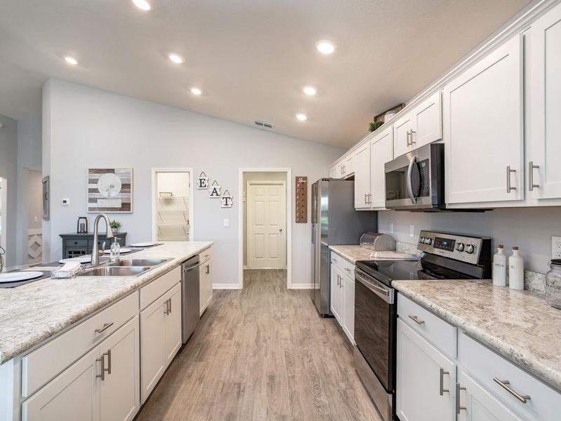 Your dream kitchen awaits, with a counter-height island, walk-in pantry, and Samsung stainless appliances - Serendipity model home in Winter Haven