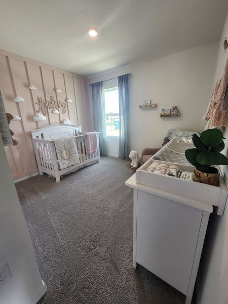 A cozy nursery with a cute white crib, soft carpeting, pastel decor, and a sunlit window creating a serene atmosphere.