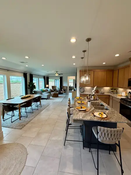 An open-concept living area with a modern kitchen, large island, and cozy dining space, featuring sleek tile flooring. An open-concept living area with a modern kitchen, large island, and cozy dining space, featuring sleek tile flooring.