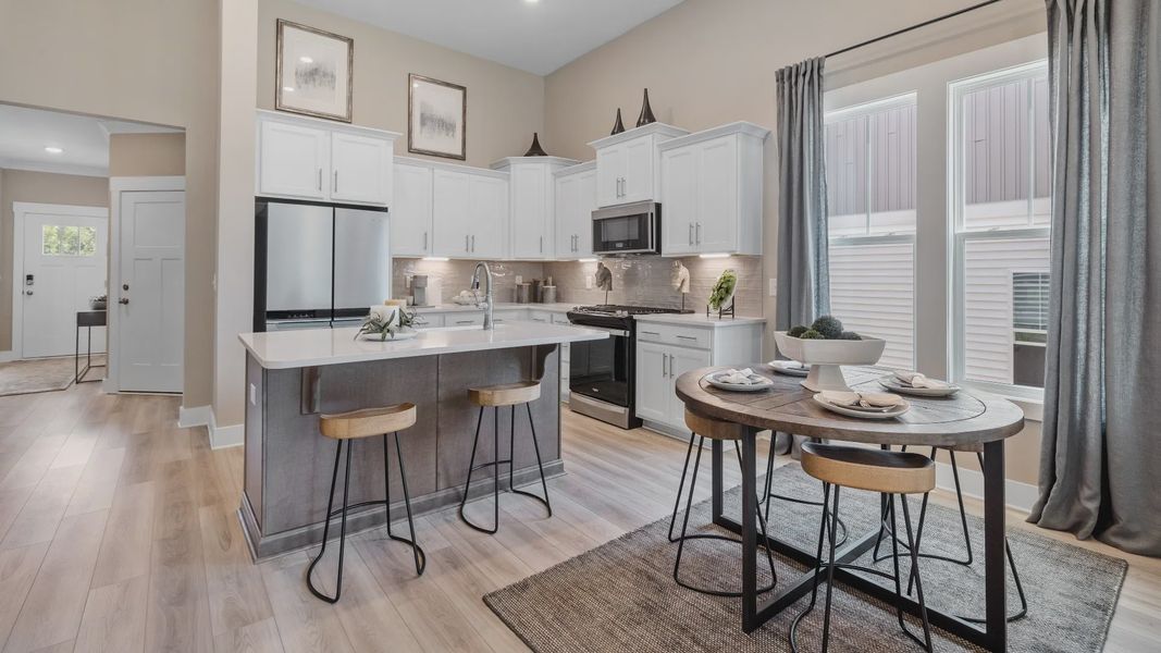 DRB Homes Summit floorplan kitchen with adjacent breakfast area plus island with room for counter stools at Pleasant Falls