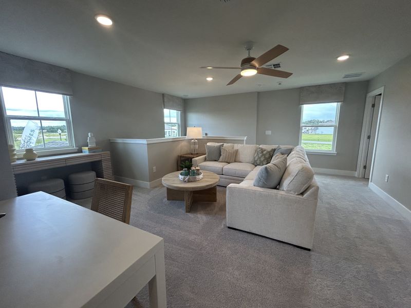 A cozy living area features a plush sectional, neutral tones, and ample natural light, creating a relaxing and inviting space.