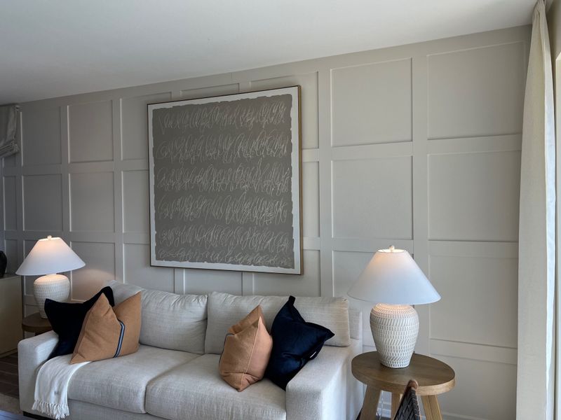 A cozy living room with a textured accent wall, comfortable sofa, elegant lamps, and abstract artwork.