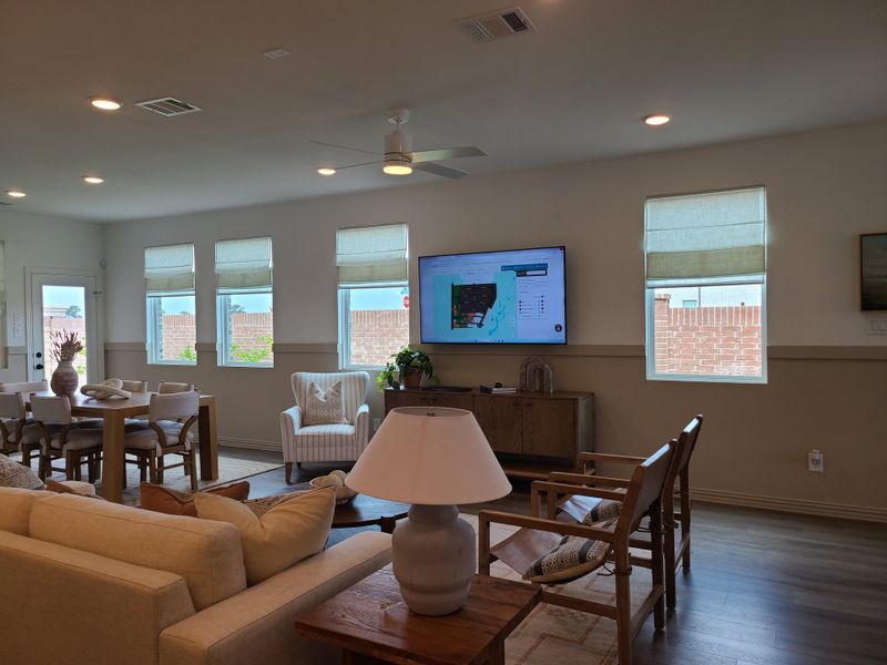A modern living room with cozy seating, a wall-mounted TV, and large windows for natural light.