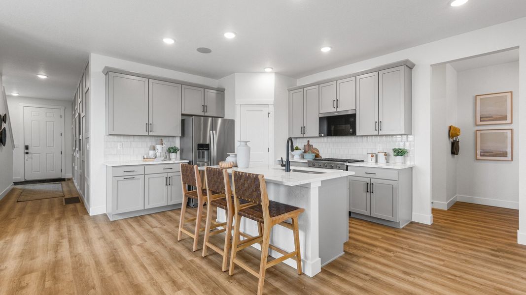 Elegant kitchen in Bloom with sleek gray cabinetry, sophisticated wood flooring, and a spacious central island.