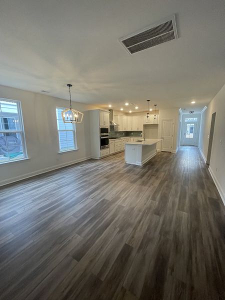 An elegant open-concept kitchen and dining area with modern fixtures, wood flooring, and large windows.