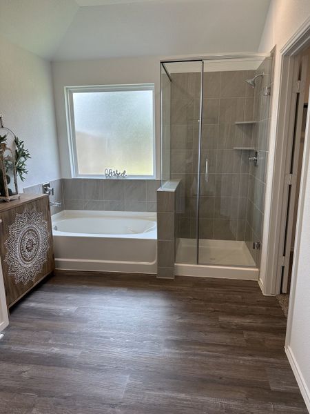A modern bathroom with a soaking tub, glass-enclosed shower, and stylish wood accents for an elegant touch.