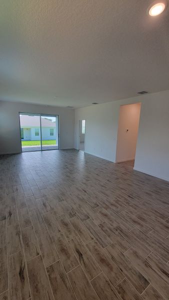 An open living space with wood-look tile flooring and large glass doors to the backyard.