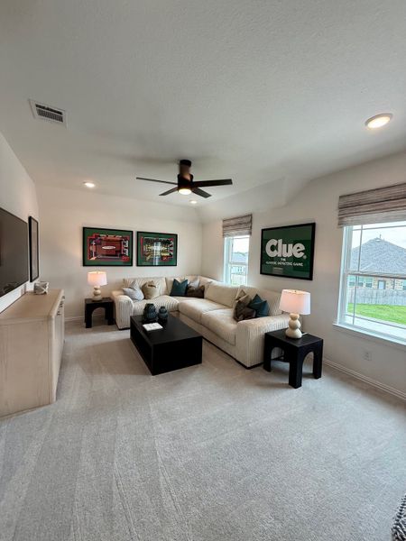 A cozy entertainment room with a plush sectional, vibrant artwork, and ambient lighting for a relaxed atmosphere.