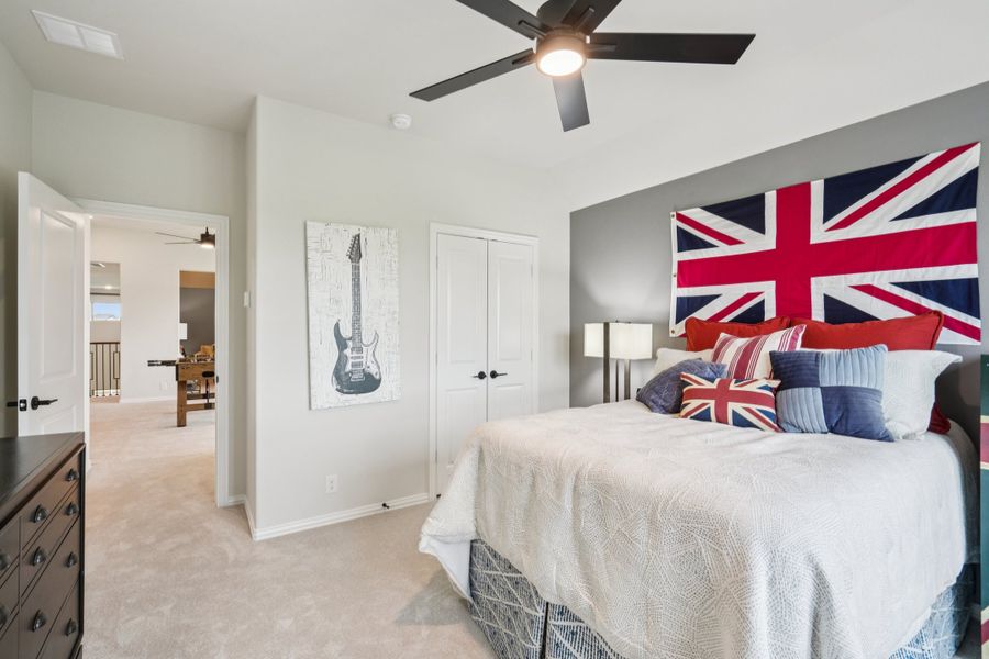 Bedroom with Union Jack flag above bed, ceiling fan, guitar wall art, and carpet flooring Bedroom with Union Jack flag above bed, ceiling fan, guitar wall art, and carpet flooring