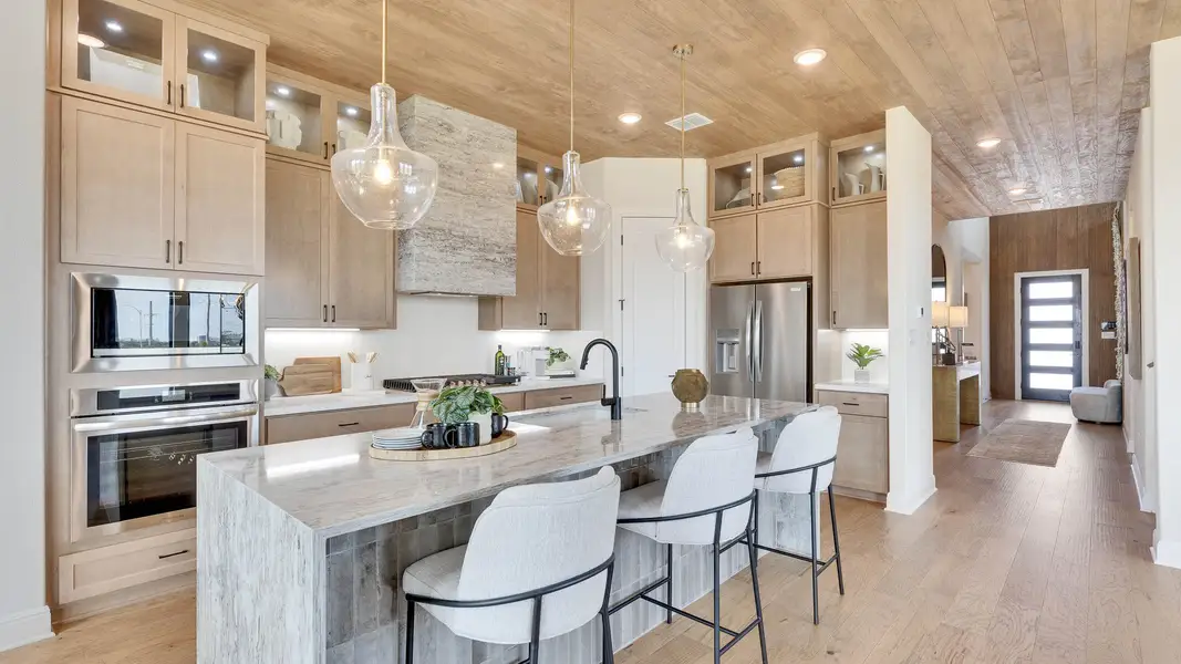 Luxurious kitchen featuring marble island, wood cabinetry, and chic pendant lighting in Lakeside Meadows. Luxurious kitchen featuring marble island, wood cabinetry, and chic pendant lighting in Lakeside Meadows.