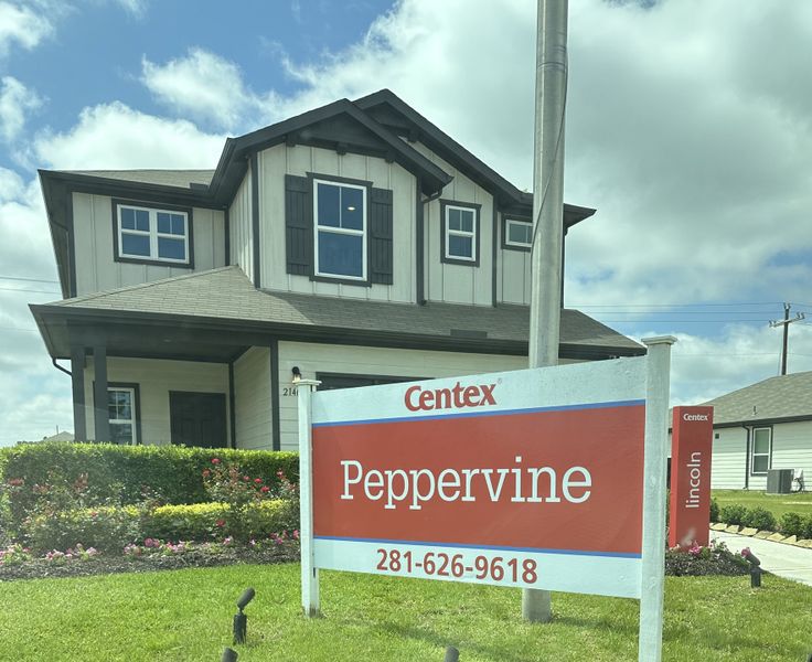 Charming two-story home with shutters and lush landscaping in Peppervine by Centex (Porter, TX).